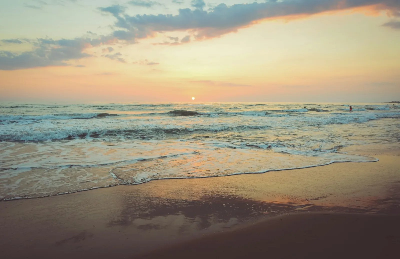 Szeroka, piaszczysta plaża nad morzem o zachodzie słońca